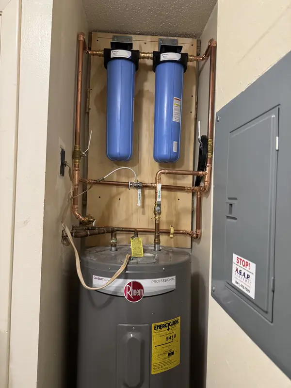 Custom two-stage whole home water filtration system with copper piping mounted above a water heater in a Longboat Key condominium